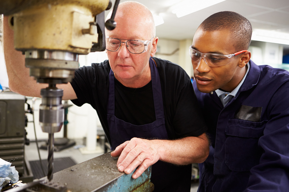 Engineer Teaching Apprentice To Use Milling Machine Engineer Teaching Apprentice To Use Milling Machine